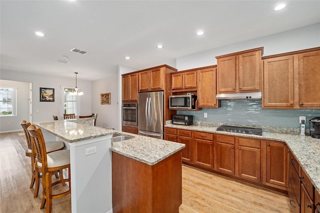 kitchen with a center island, hanging light fixtures, light stone counters, a chandelier, and appliances with stainless steel finishes