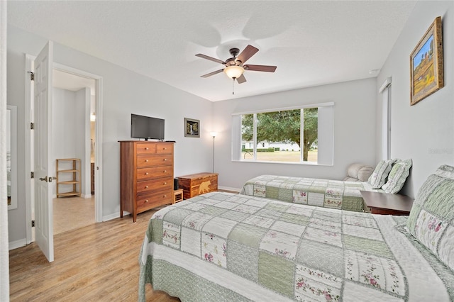 bedroom featuring a textured ceiling, light wood-type flooring, and ceiling fan