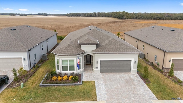 view of front of property with a front yard, a rural view, and a garage