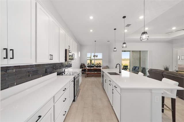 kitchen with a spacious island, decorative light fixtures, stainless steel appliances, sink, and backsplash