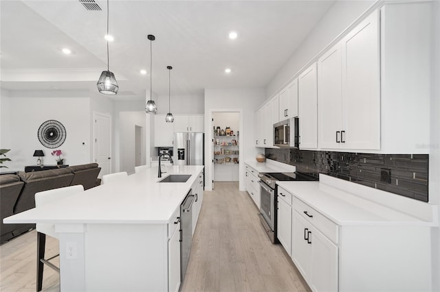 kitchen with a spacious island, hanging light fixtures, appliances with stainless steel finishes, a breakfast bar area, and white cabinets