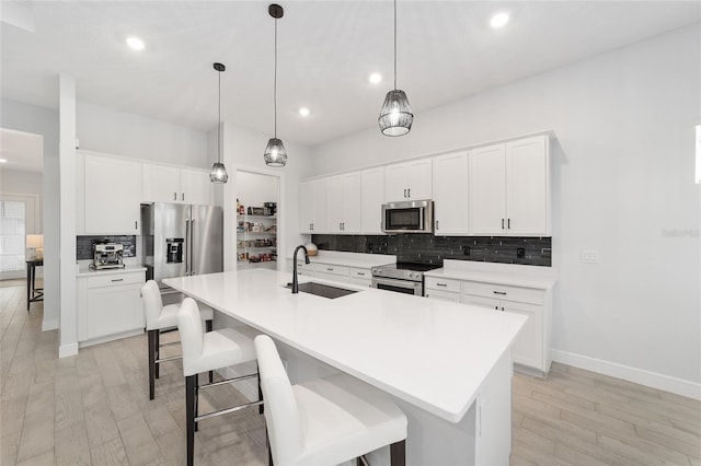 kitchen featuring stainless steel appliances, an island with sink, white cabinetry, and sink