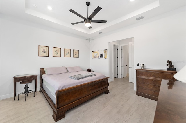 bedroom featuring ceiling fan, a tray ceiling, and light hardwood / wood-style floors