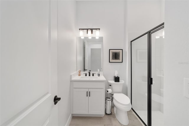 bathroom with an enclosed shower, vanity, and toilet