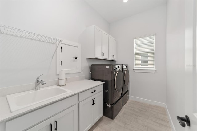 washroom featuring cabinets, sink, light hardwood / wood-style flooring, and washing machine and dryer