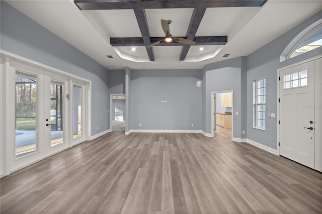 unfurnished living room with beam ceiling, ceiling fan, french doors, coffered ceiling, and light hardwood / wood-style flooring