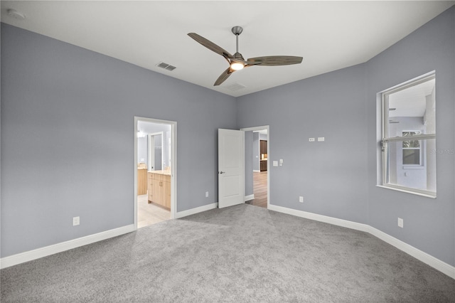 unfurnished bedroom with connected bathroom, light colored carpet, and ceiling fan