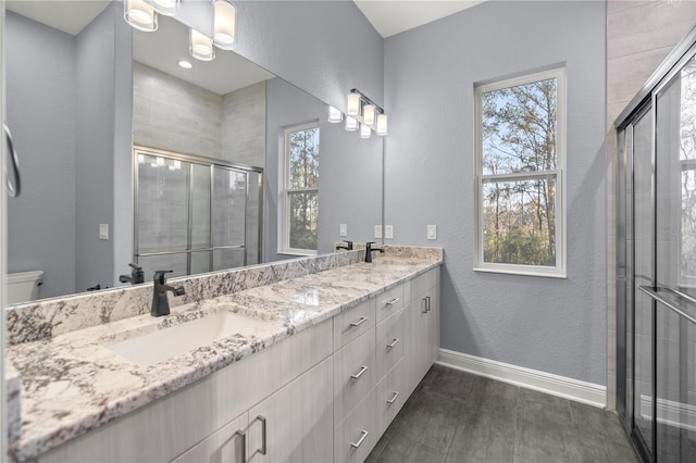 bathroom with plenty of natural light, vanity, a shower with shower door, and wood-type flooring