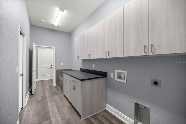 laundry area with electric dryer hookup, cabinets, washer hookup, light wood-type flooring, and a textured ceiling