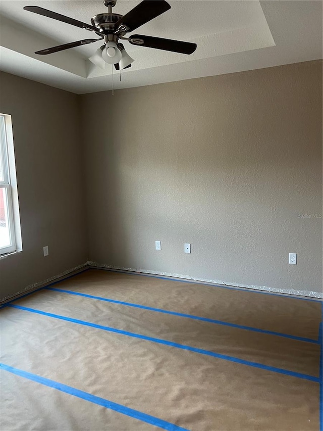 carpeted empty room featuring ceiling fan and a tray ceiling