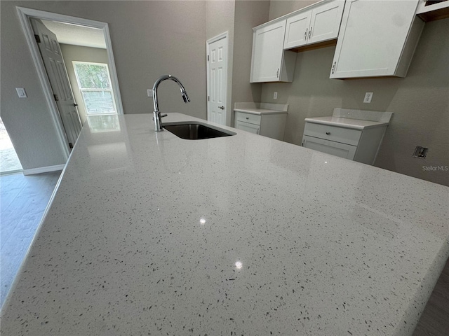 kitchen with light stone counters, sink, and white cabinets