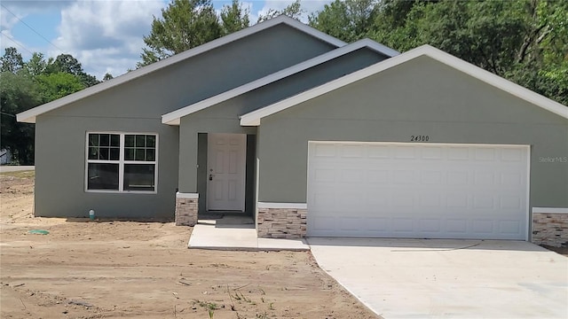 24300 SW Sea Cliff Ave, Dunnellon, FL 34431 - view of front facade with an attached garage, stucco siding, stone siding, and concrete driveway