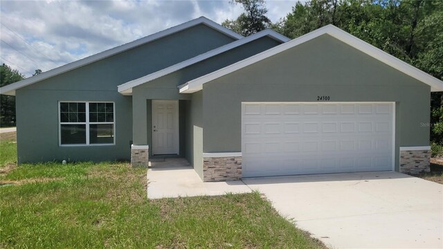 24300 SW Sea Cliff Ave, Dunnellon, FL 34431 - view of front of home with a garage, stucco siding, concrete driveway, stone siding, and a front lawn