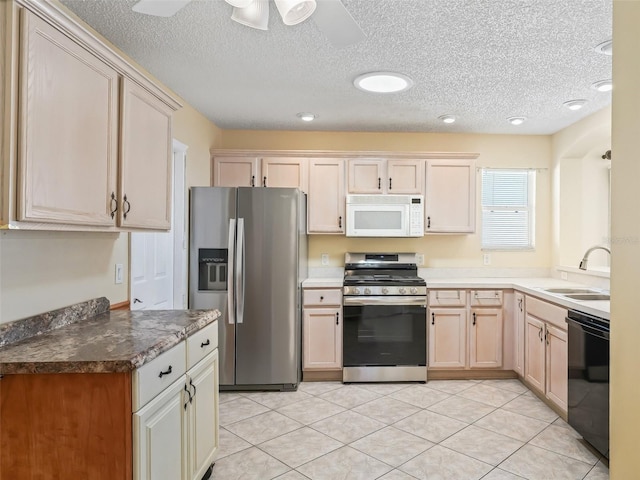 kitchen with light tile patterned floors, a textured ceiling, appliances with stainless steel finishes, and a sink