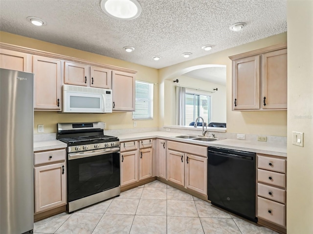 kitchen with light brown cabinets, appliances with stainless steel finishes, light countertops, and a sink