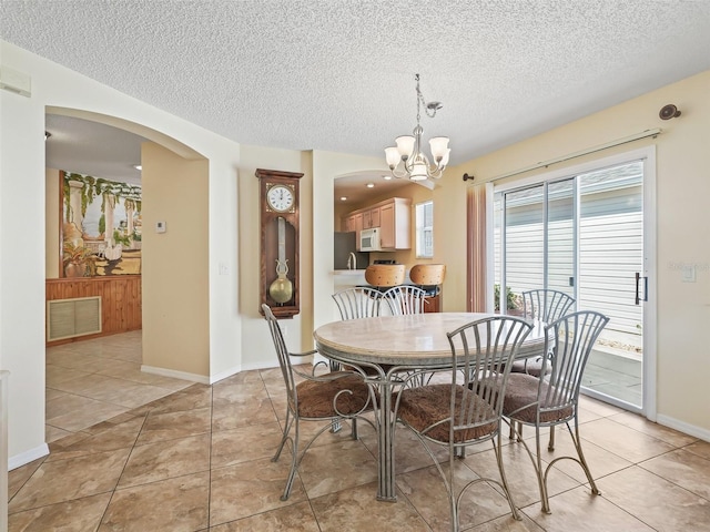 dining room with light tile patterned floors, visible vents, arched walkways, and an inviting chandelier