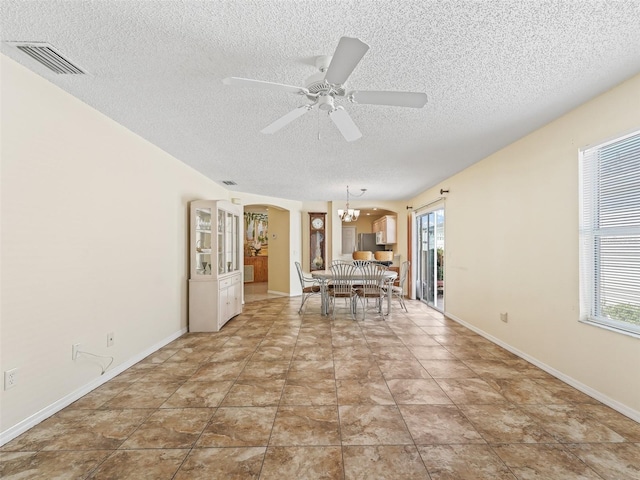 unfurnished dining area with plenty of natural light, visible vents, arched walkways, and ceiling fan with notable chandelier