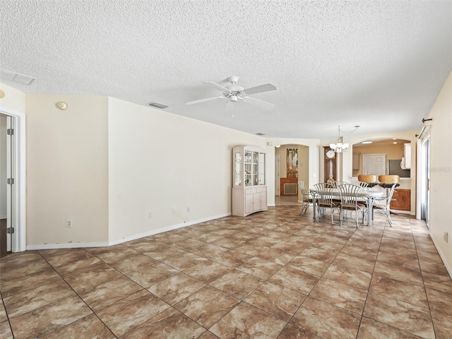 unfurnished living room with baseboards, visible vents, arched walkways, a textured ceiling, and ceiling fan with notable chandelier