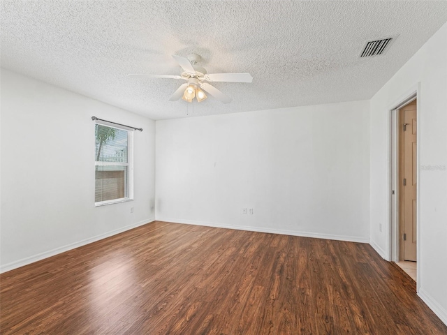 empty room featuring a ceiling fan, baseboards, visible vents, and wood finished floors