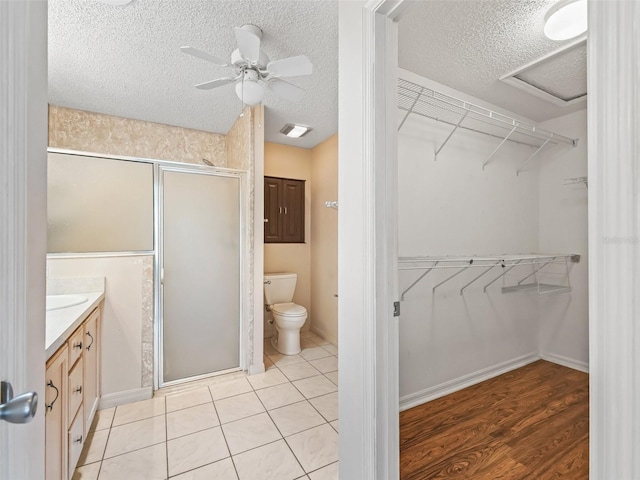 bathroom featuring a textured ceiling, toilet, visible vents, vanity, and a shower stall