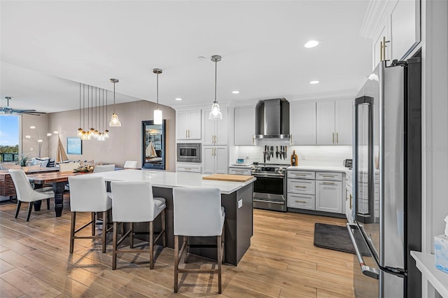 kitchen featuring white cabinets, pendant lighting, wall chimney exhaust hood, and stainless steel appliances