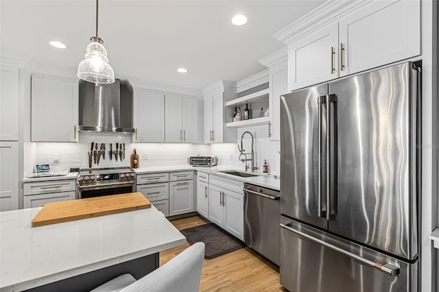 kitchen featuring sink, white cabinetry, high end appliances, and wall chimney range hood