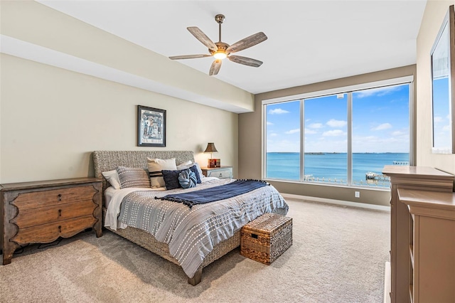 bedroom featuring carpet flooring, ceiling fan, and a water view