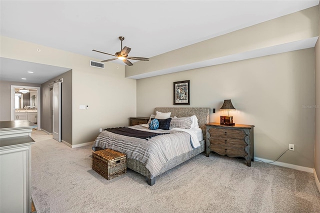 carpeted bedroom with ensuite bath and ceiling fan