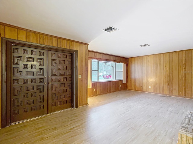 unfurnished living room with wood walls and light hardwood / wood-style flooring