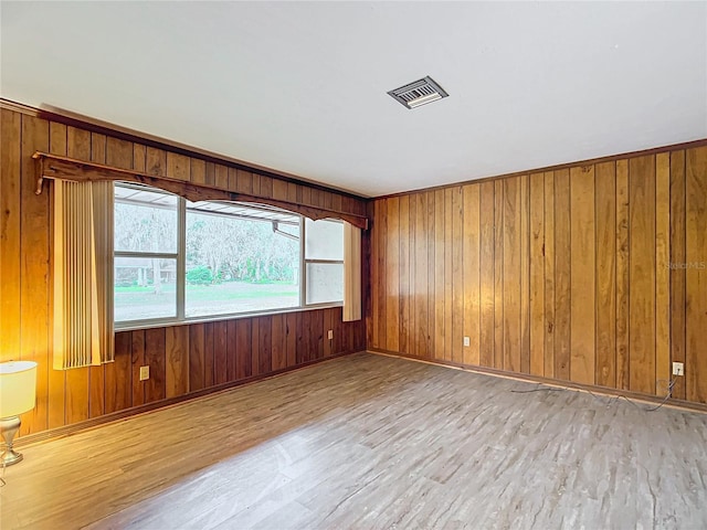 unfurnished room with light hardwood / wood-style floors and wooden walls