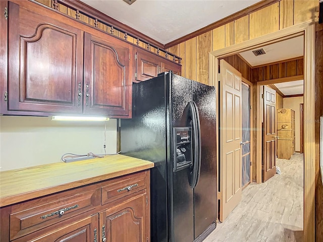 kitchen with black refrigerator with ice dispenser, wooden walls, and crown molding