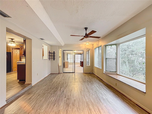 unfurnished room featuring a textured ceiling, ceiling fan, and light hardwood / wood-style flooring