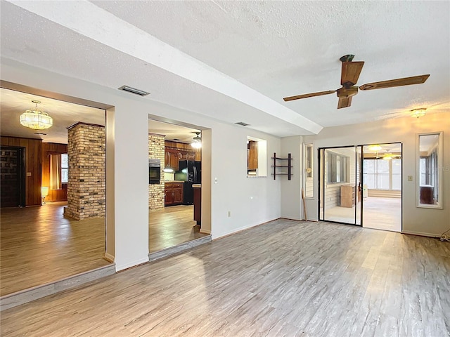 unfurnished living room with light hardwood / wood-style floors, ceiling fan, a textured ceiling, and brick wall