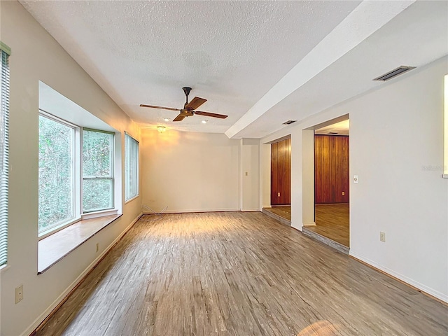 spare room featuring a textured ceiling, ceiling fan, and light wood-type flooring