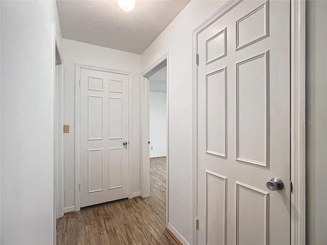 hallway with wood-type flooring and a textured ceiling