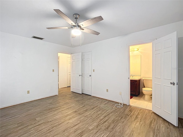 unfurnished bedroom with ensuite bath, ceiling fan, and light hardwood / wood-style flooring