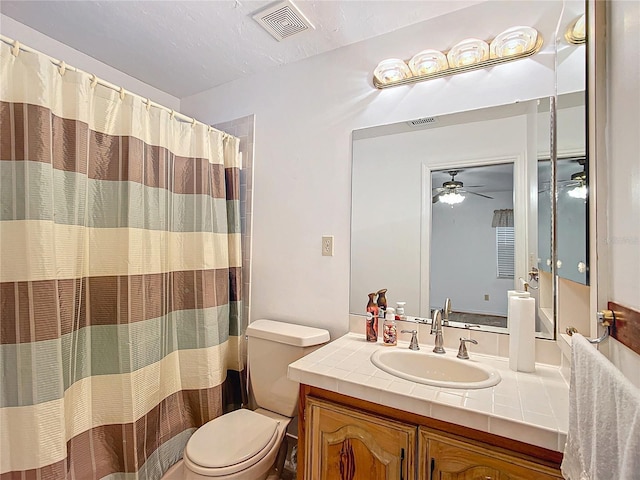 bathroom featuring toilet, ceiling fan, walk in shower, and vanity