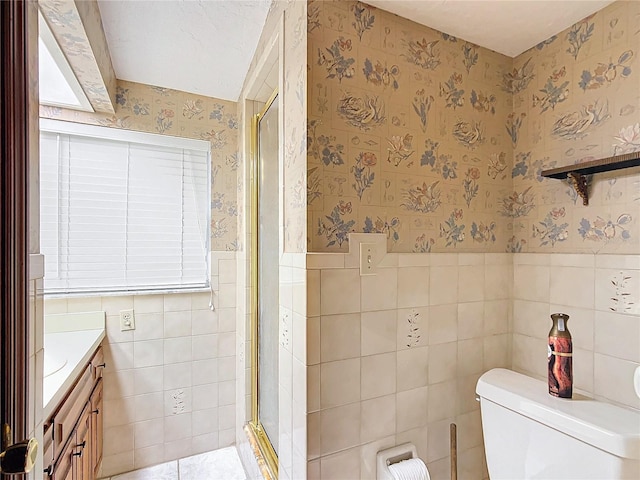 bathroom with tile walls, an enclosed shower, vanity, and toilet