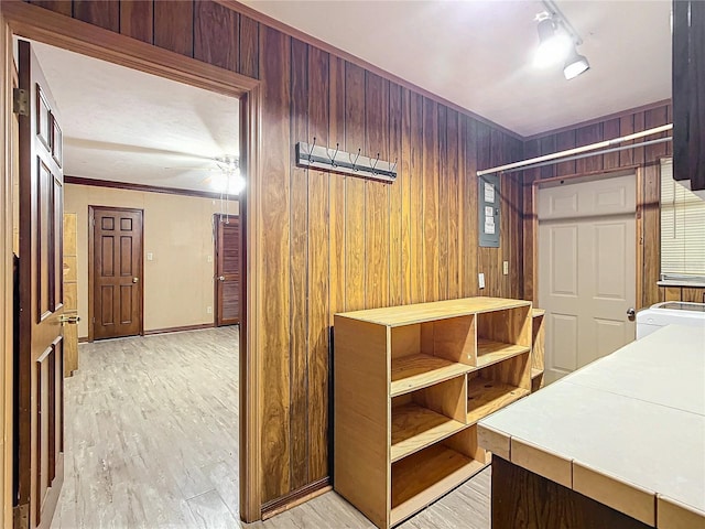 corridor with light wood-type flooring and wooden walls