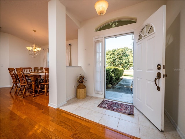 tiled entryway with an inviting chandelier and lofted ceiling