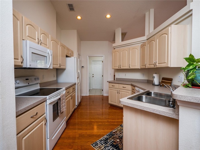 kitchen with light brown cabinetry, sink, white appliances, and dark hardwood / wood-style floors