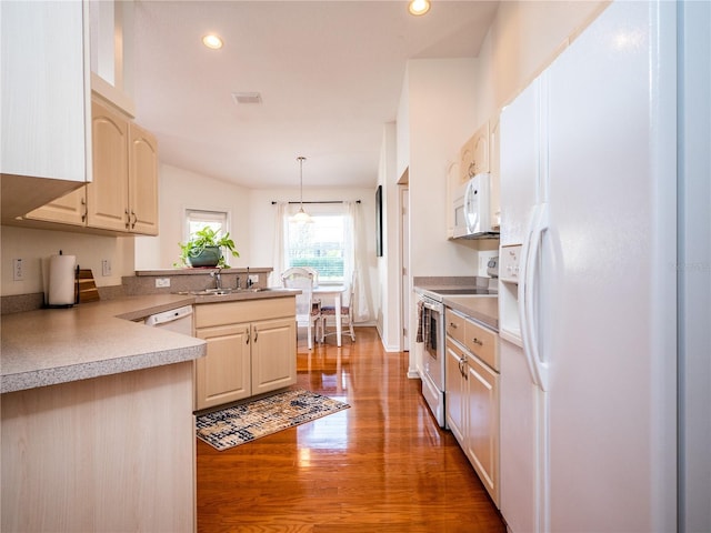 kitchen with sink, kitchen peninsula, pendant lighting, white appliances, and hardwood / wood-style floors