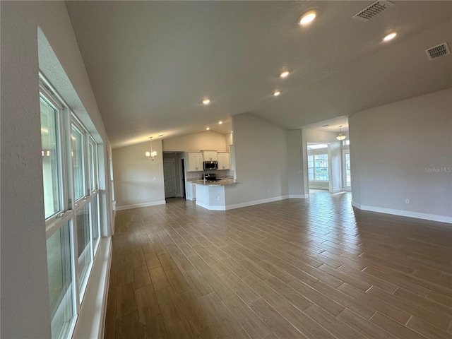 unfurnished living room with a notable chandelier and vaulted ceiling