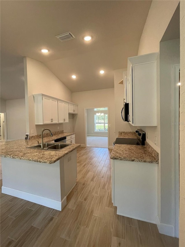 kitchen with white cabinets, range, light stone countertops, kitchen peninsula, and sink