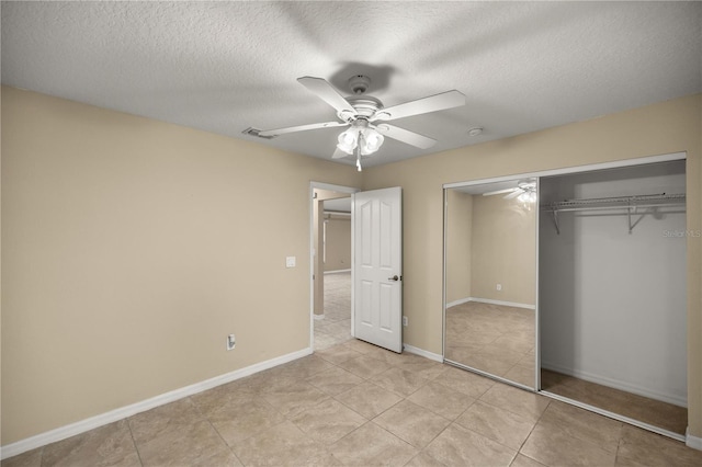 unfurnished bedroom featuring ceiling fan, light tile patterned floors, a textured ceiling, and a closet