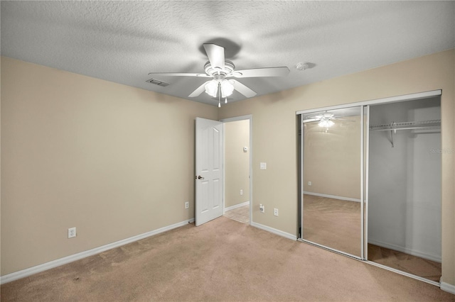 unfurnished bedroom featuring a textured ceiling, ceiling fan, light carpet, and a closet