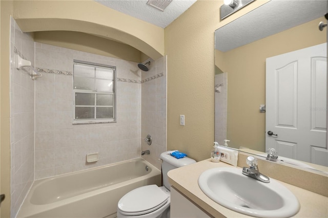 full bathroom with toilet, vanity, a textured ceiling, and tiled shower / bath