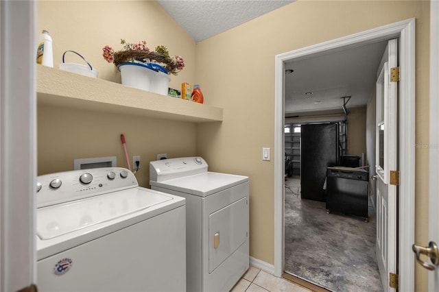 laundry area with a textured ceiling, washer and clothes dryer, and light tile patterned flooring