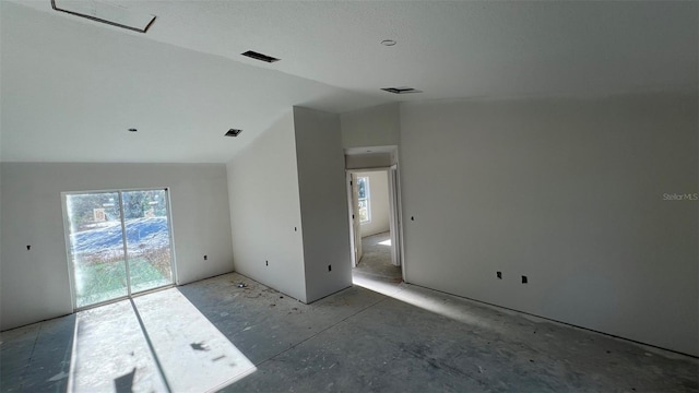 empty room featuring a healthy amount of sunlight and vaulted ceiling