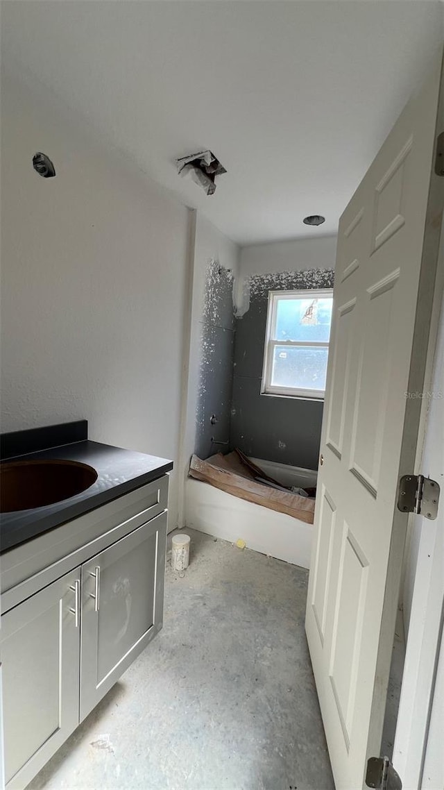 bathroom with vanity, a bath, and concrete floors